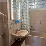 Badezimmer mit Badewanne, Spiegel und Duschvorhang mit Muster.