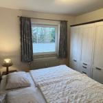 Schlafzimmer mit Bett, Kleiderschrank und Fenster mit Vorhängen.