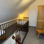 Zimmer mit Dachschrägen, Bett, Kleiderschrank und Stuhl.