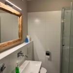Bad mit Dusche, Waschbecken und Spiegel mit Holzrahmen