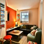 Wohnzimmer mit Sofa, Sessel und Couchtisch. Wandregal mit Büchern und Fenster.