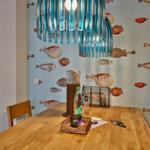 Esszimmer mit Fisch壁纸, Holztisch und blauem Hängelicht.