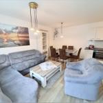 Living room with sofa, armchair, dining table, and kitchen.