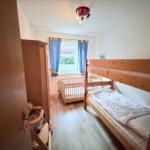 A bedroom with a bunk bed and a crib.