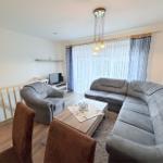 Living room with gray sofa, coffee table, and TV. Windows with curtains.
