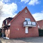 Red brick building with balcony and terrace under blue sky.