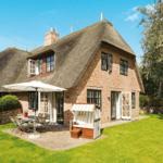 House with thatched roof, terrace, garden, and beach chair.