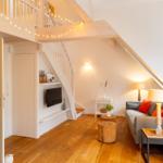 Wohnbereich mit Sofa, Fernseher und Holzboden unter Dachschrägen.