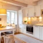 Küche mit Essbereich, weißen Schränken und Holzdecke.