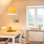 Essbereich mit Tisch, Stühlen und Fenster. Auf dem Tisch steht ein Brötchen.