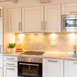 Küche mit weißen Schränken, Herd, Spüle und Mikrowelle.