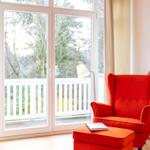 Rotes Sessel mit Fußhocker vor Glasfront zum Balkon