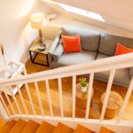 Wohnzimmer mit Sofa, Tisch und Stühlen unter Dachschrägen.