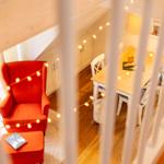 Ein Raum mit rotem Sessel, Esstisch und warmen Lichterketten.