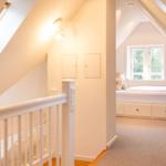 Dachgeschosszimmer mit Bett und Fenster. Blick von der Treppe.