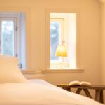 Schlafzimmer mit Bett, Tisch, Lampe und offener Tür.