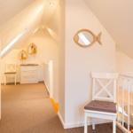 Dachgeschoss mit Stufen, Stuhl und Spiegel an der Wand.