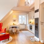 Wohnküche mit Essbereich, rotem Sessel und Dachbodenbereich.