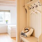 Ein Flur mit Garderobe und Blick in ein Schlafzimmer mit Fenster und Bett.