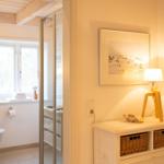 Badezimmer mit Dusche und Toilette. Nebenraum mit Schrank, Lampe und Bild.