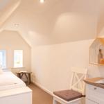 Schlafzimmer mit Dachschrägen, Bett, Stuhl und Schreibtisch.