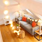 Wohnzimmer mit Sofa, Tischen und Lichterkette unter Holzdecke.