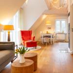 Wohn- und Essbereich mit Holzboden, rotem Sessel und Tisch mit Stühlen.