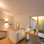 Arbeitszimmer mit Holztisch, Stuhl und Fenster. Wanddekoration und Heizung sind sichtbar.