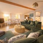 Wohnzimmer mit grünem Sofa, runden Tisch und Holzbalken an der Decke.