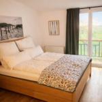 Schlafzimmer mit Doppelbett, Balkon und Holzboden.