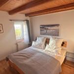 Schlafzimmer mit Holzboden, Bett und Fenster. Decke mit Holzbalken.