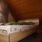 Bedroom with wooden ceiling and bed with bedding.