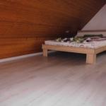 Bedroom with wooden floor and wall, bed with bedding