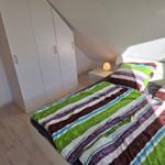 Bedroom with sloped ceiling, white wardrobe, and bed with colorful bedding.