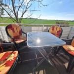 Terrace with table and four chairs, view of green fields.