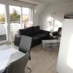 Living and dining area with sofa, table and chairs. Access to terrace with view of field.