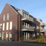 Moderne Mehrfamilienhaus mit Balkonen und Ziegelfassade.