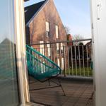 Terrasse mit blauer Sitzgelegenheit und Blick auf ein Haus.