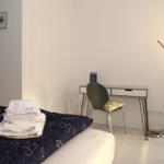Schlafzimmer mit Bett, Schreibtisch und Stehlampe.