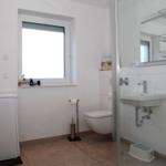 Badezimmer mit Waschmaschine, Toilette und Dusche.