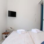 Zimmer mit Doppelbett, Fernseher und Fenster. Handtücher und Körbchen sind vorhanden.