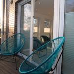 Terrasse mit zwei türkisfarbenen Sesseln und Blick in das Wohnzimmer.