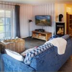 Wohnzimmer mit Kamin, Sofa und TV. Durchgang zur Terrasse.