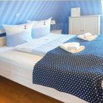 Schlafzimmer mit Bett, Kissen und blauer Wandtapete mit Streifen.