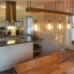 Küche mit Holztablett und hängenden Lampen. Fenster mit Jalousien und Blumen in Glasvase.