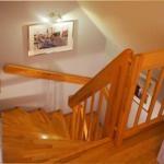 Holzgetreppe mit Geländer führt nach oben. Wandbild zeigt Schiffe. Raum mit hellem Holzboden.