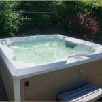 Ein Whirlpool mit Sprudelwasser steht auf einer Steinplattform umgeben von Bäumen.