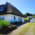 Wohnhaus mit strohgedecktem Dach und gepflasterter Einfahrt.