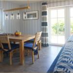 Essbereich mit Holztisch und Stühlen, Sofa und Fenster zur Terrasse.