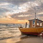 Holzboot Meereswelle am Strand bei Sonnenuntergang mit Wellen und Himmel.